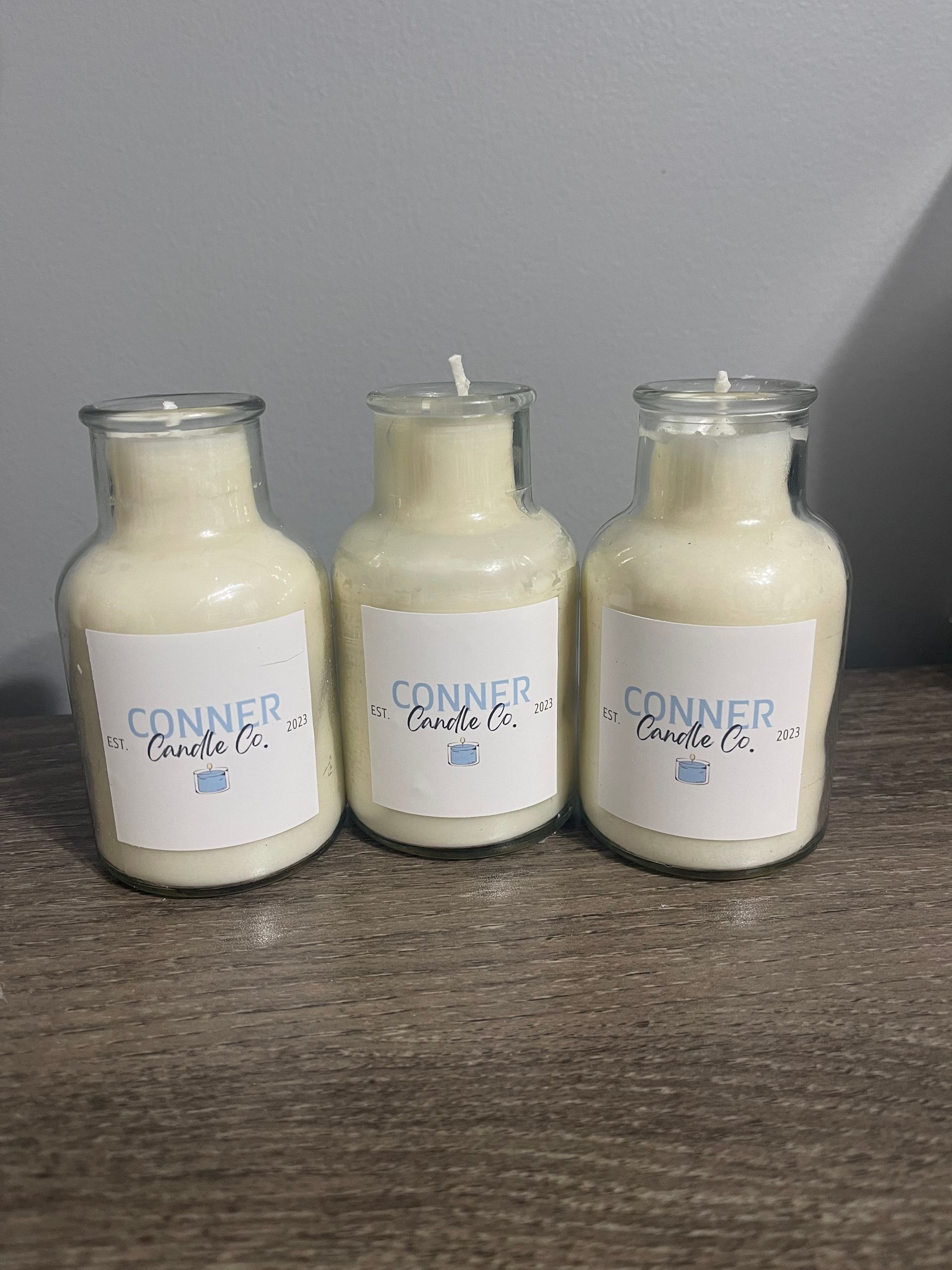 Cream-colored candle in a clear glass bottle, labeled 