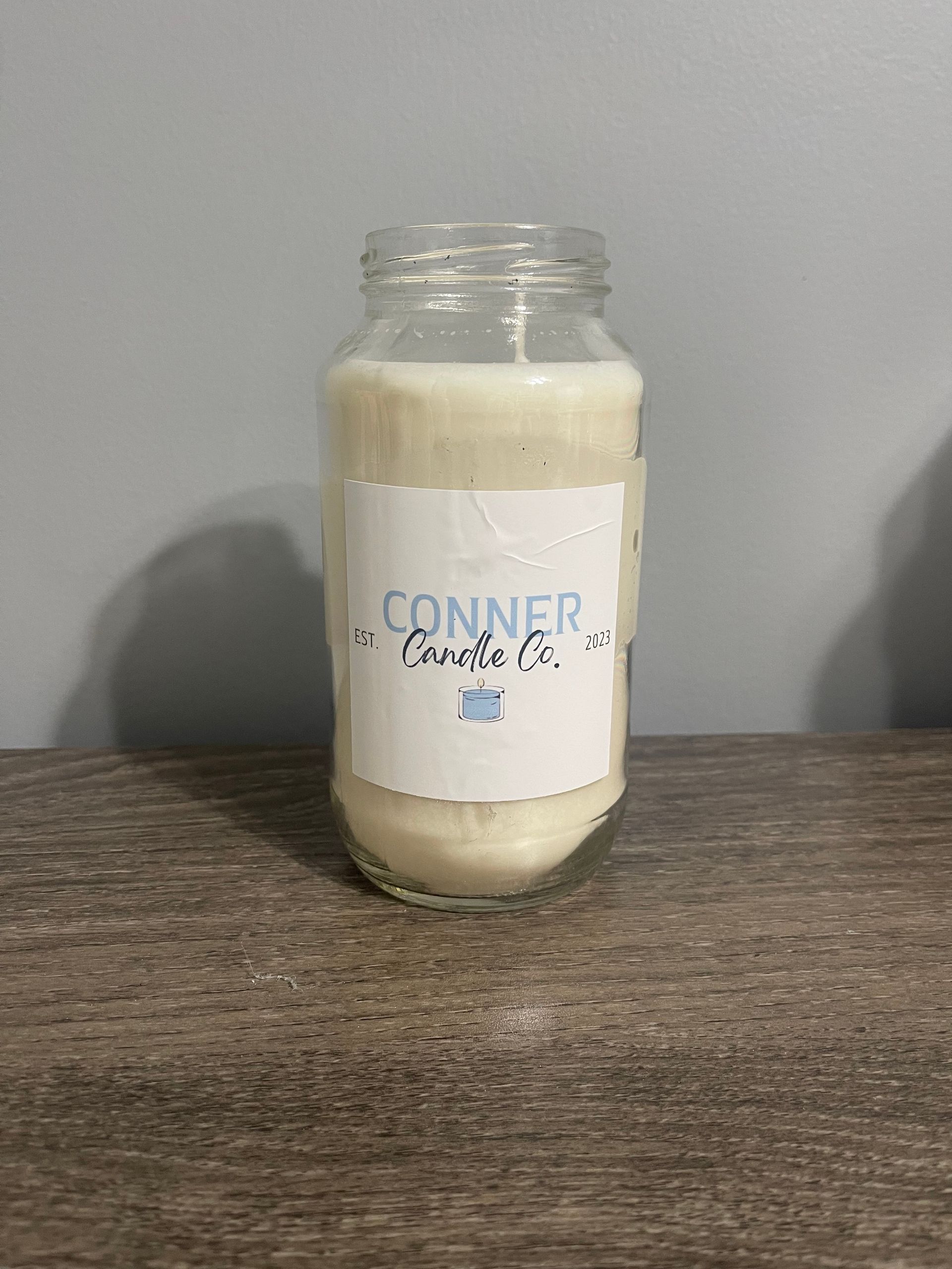 White candle in a glass jar with label that reads 