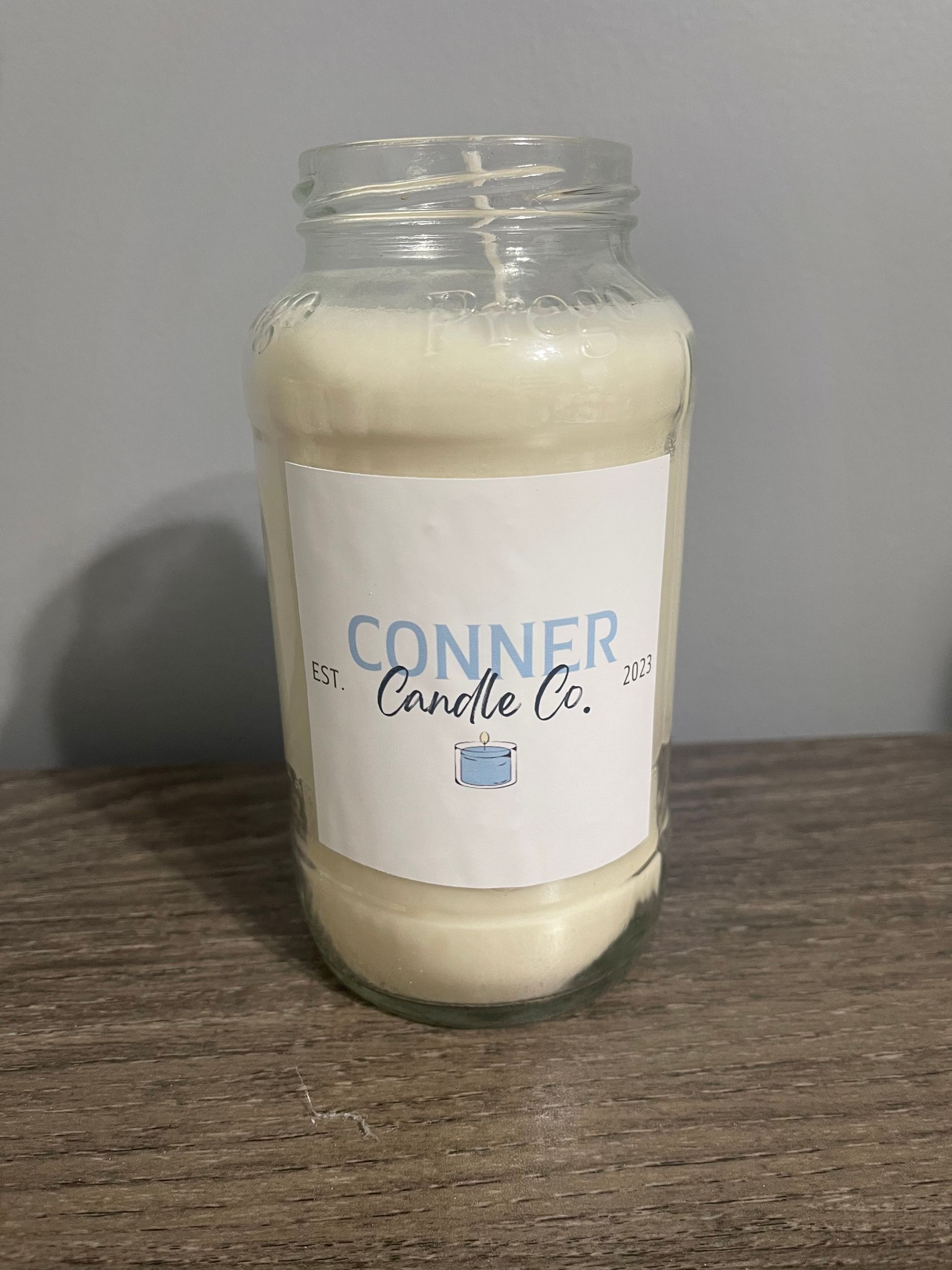 White candle in a jar with a label that says 