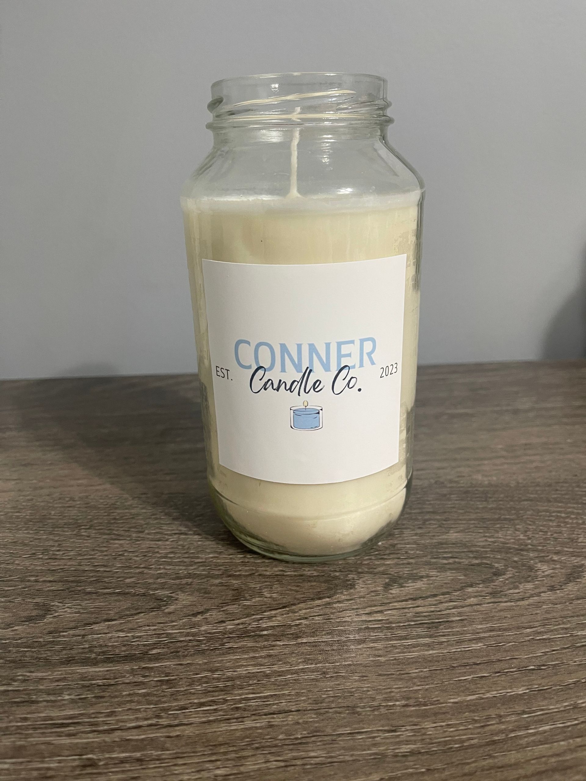 White candle in a glass jar, labeled 