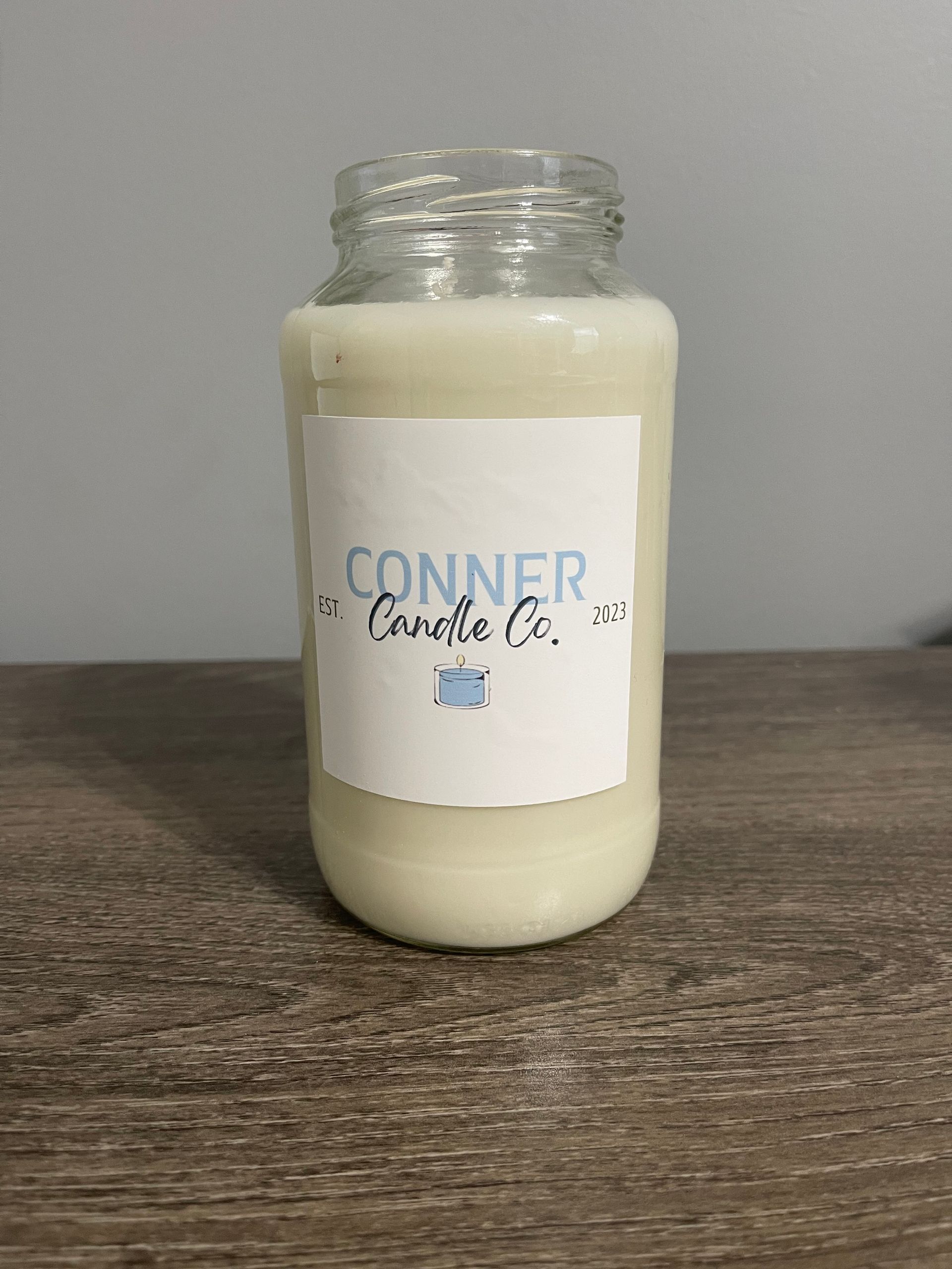 A candle in a clear glass jar with a white label that reads 