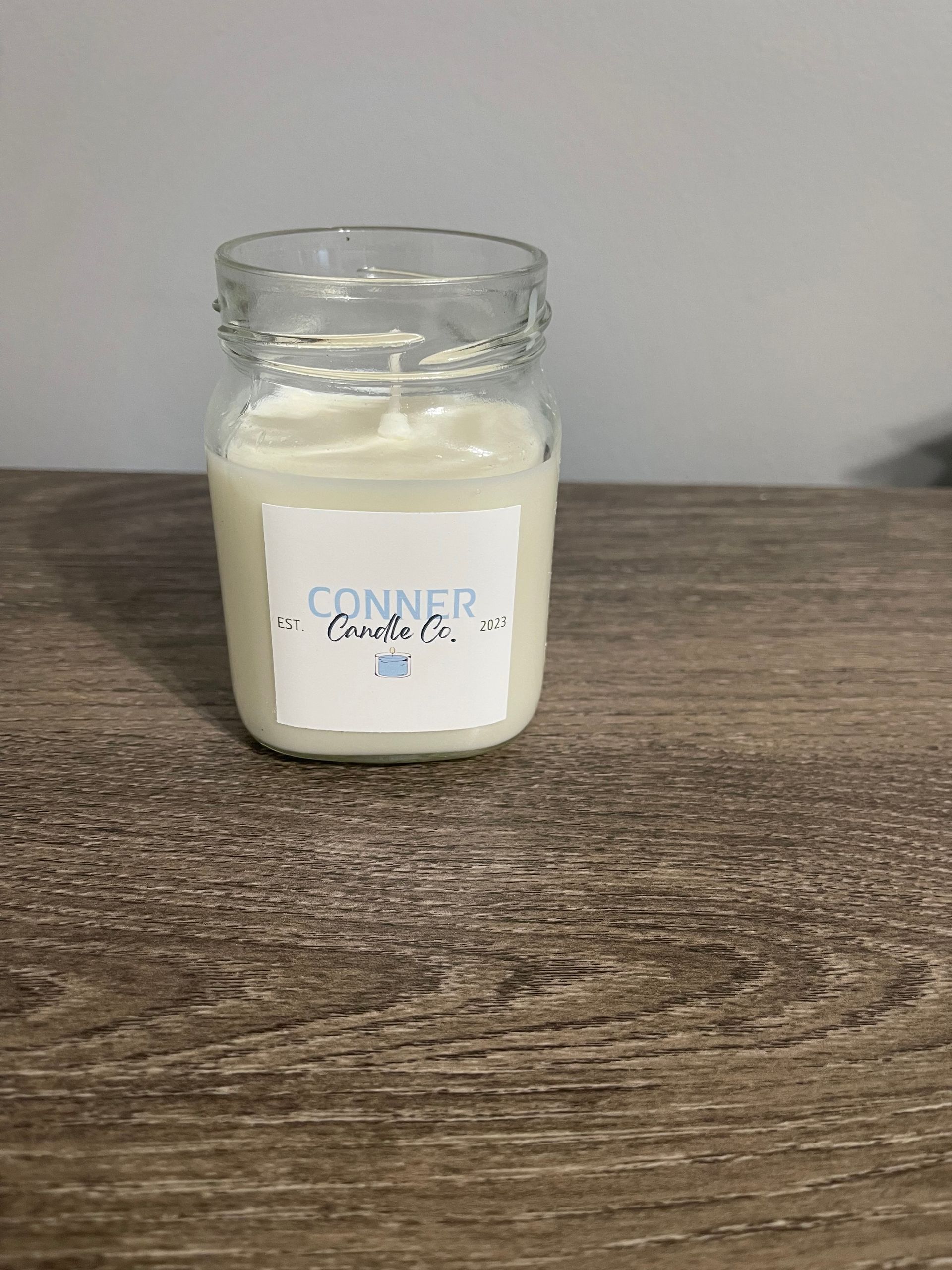 Clear glass jar candle on a wood surface, with the label 