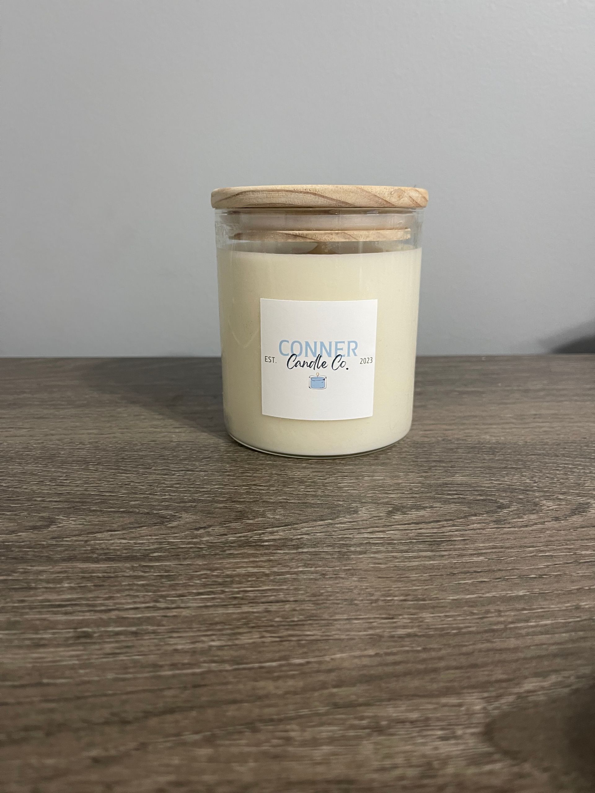 Candle in a glass jar with a wooden lid, labeled "Connell Candle Co.".