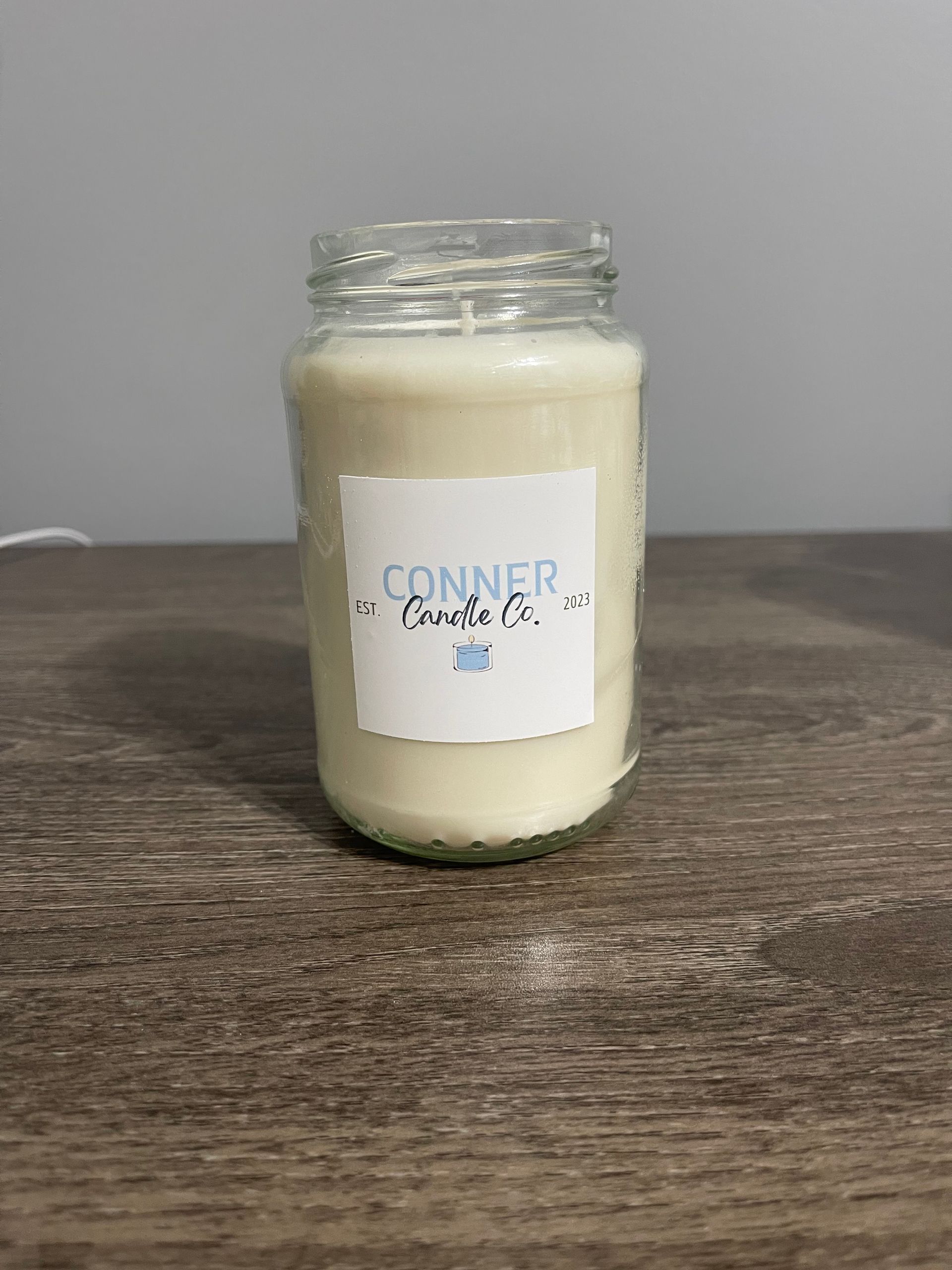 White candle in a glass jar with a label that says 