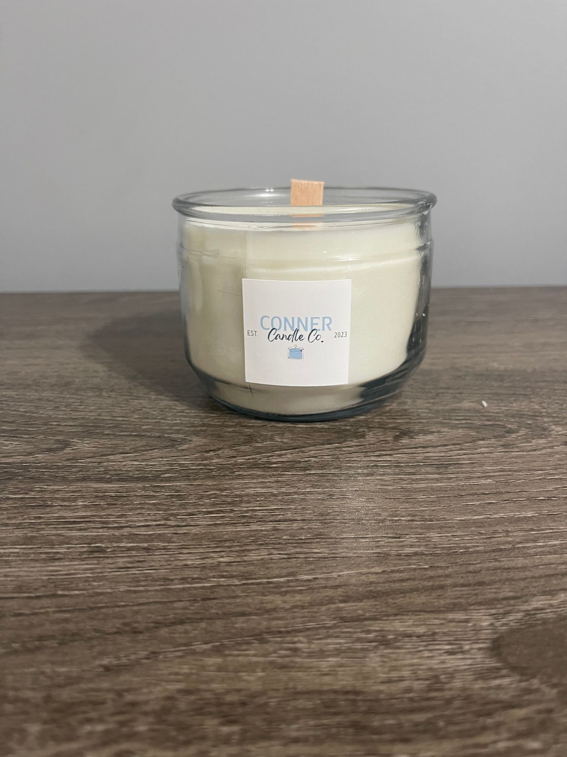 Glass jar candle with wood wick; label reads 