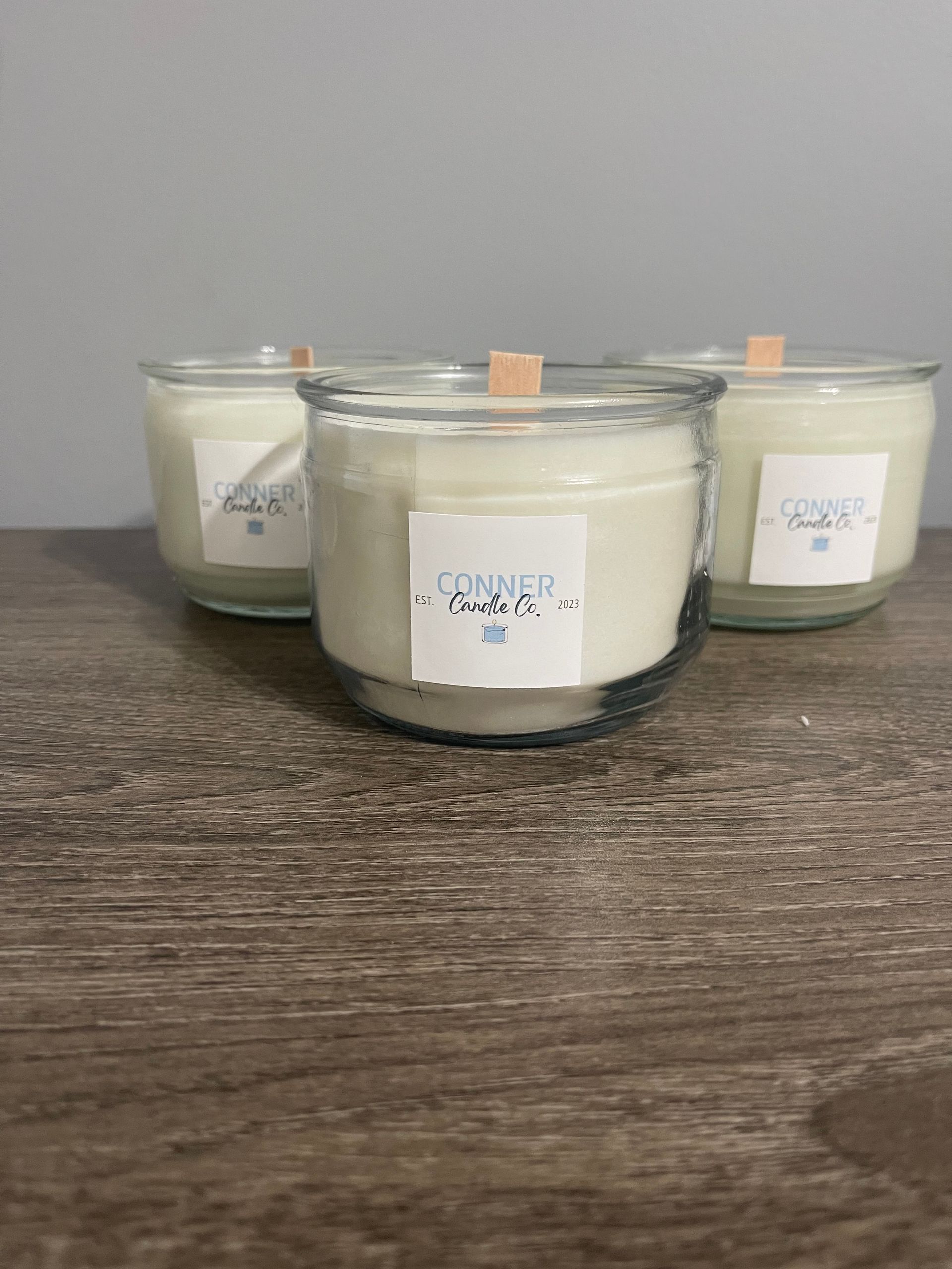 Glass jar candle with wood wick; label reads 