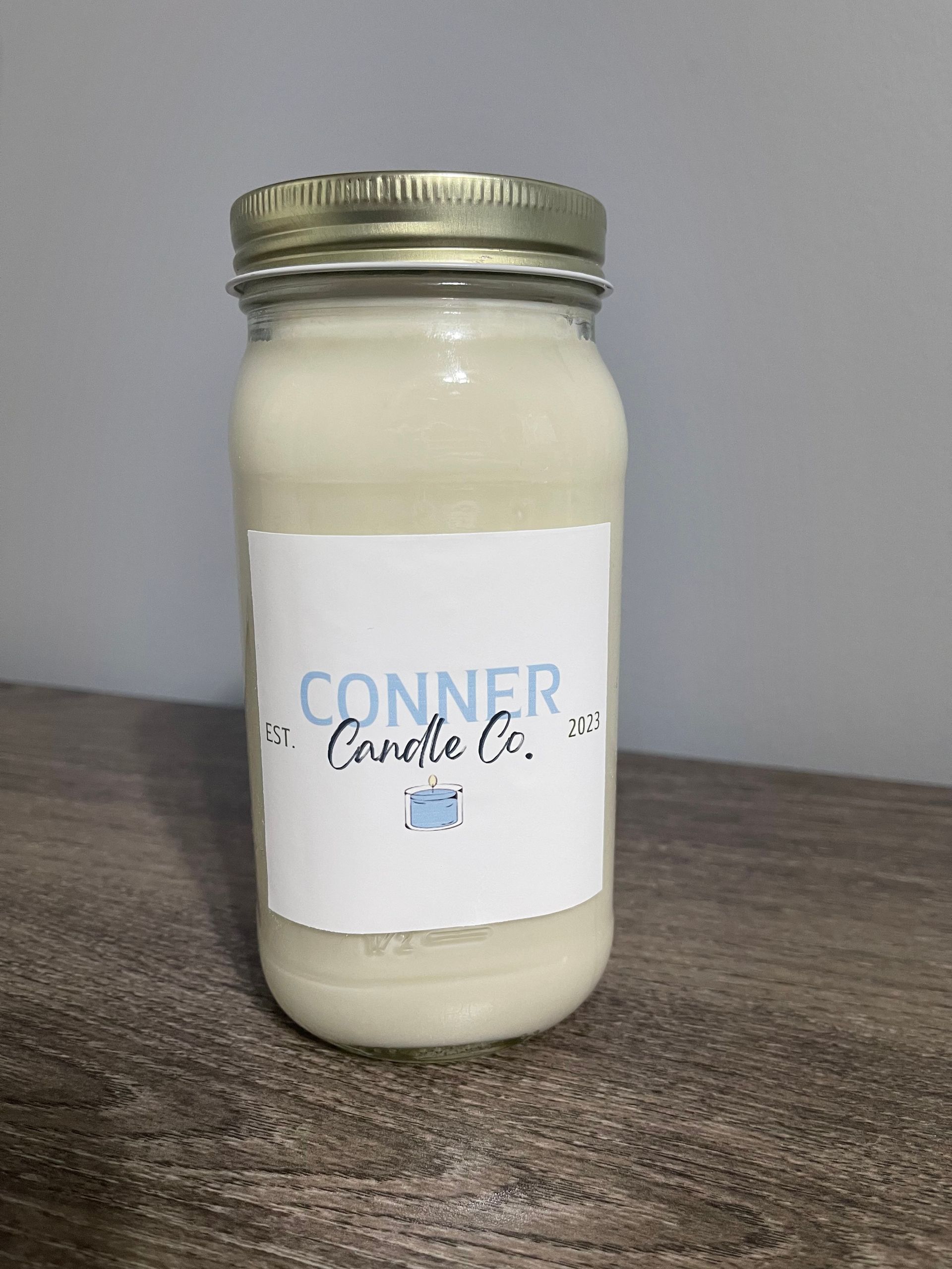 Three cream-colored jar candles with labels that read 