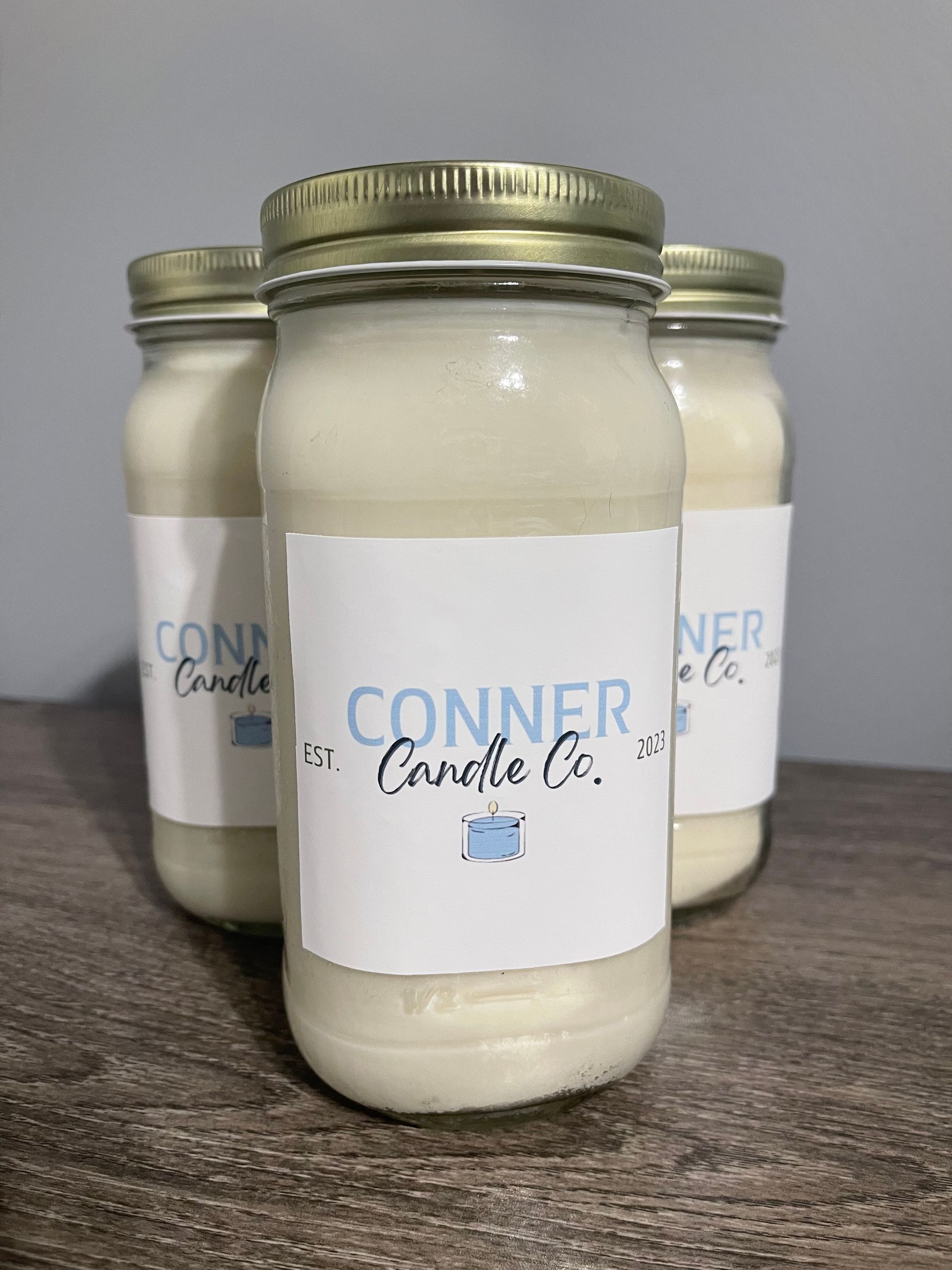 Three cream-colored jar candles with labels that read 