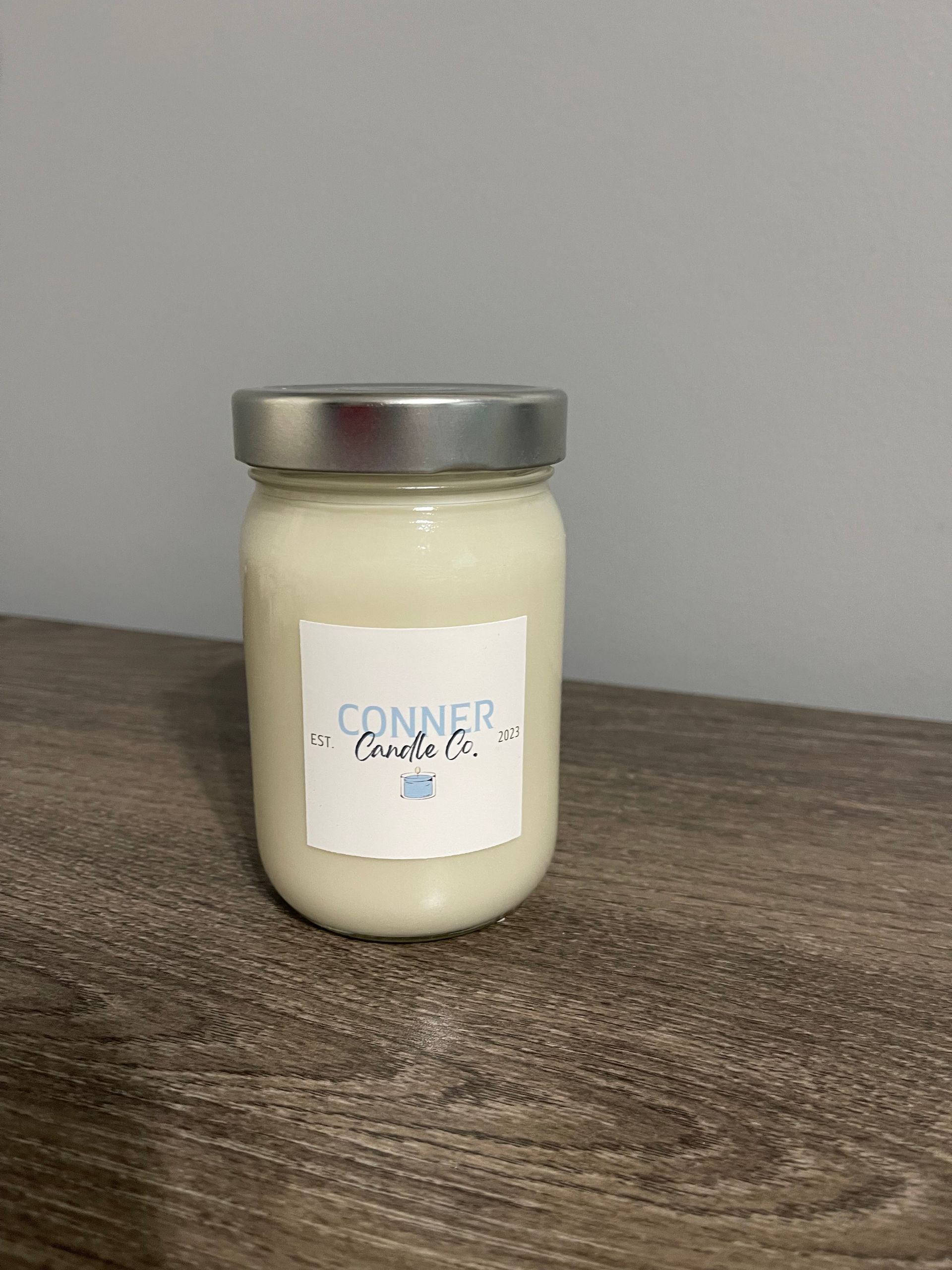 Mason jar candle with silver lid and a white label that says 