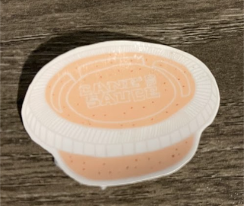 A single-serve cup of sauce with the text 