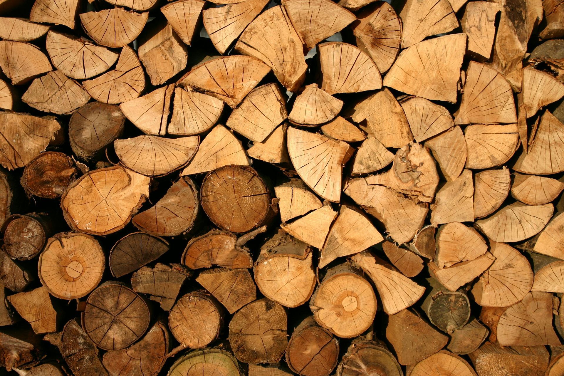 Pile of stacked firewood, varying in size and color, ready for burning.