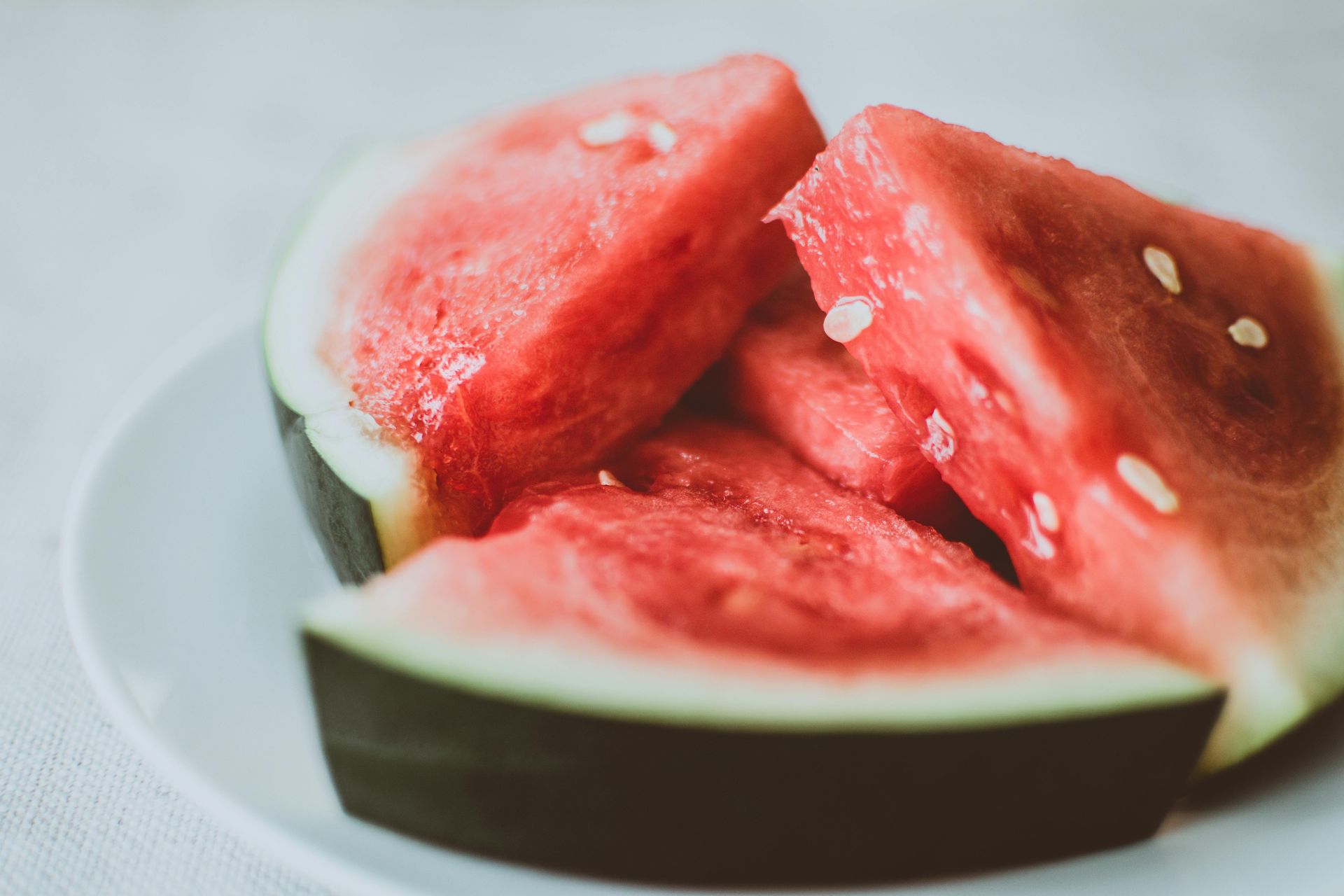 Watermelon wedges on a white plate; red flesh, black rind.