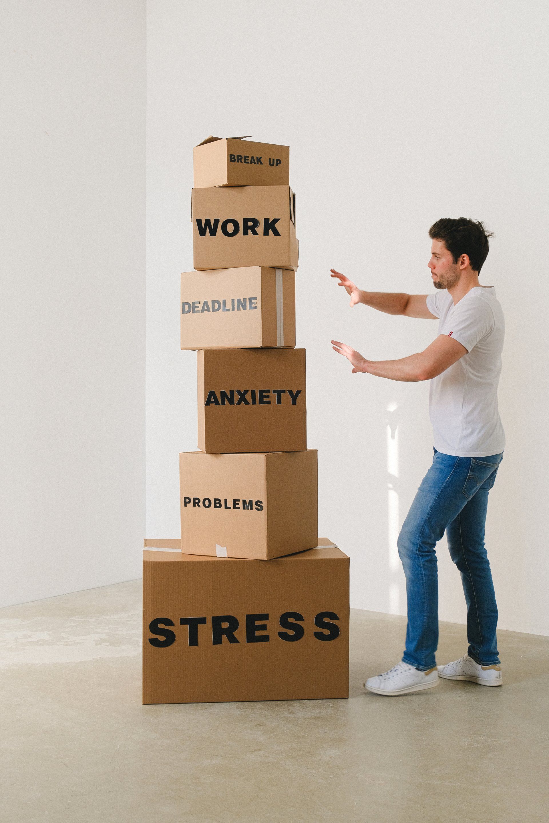 Man gestures away from a precarious stack of labeled boxes: