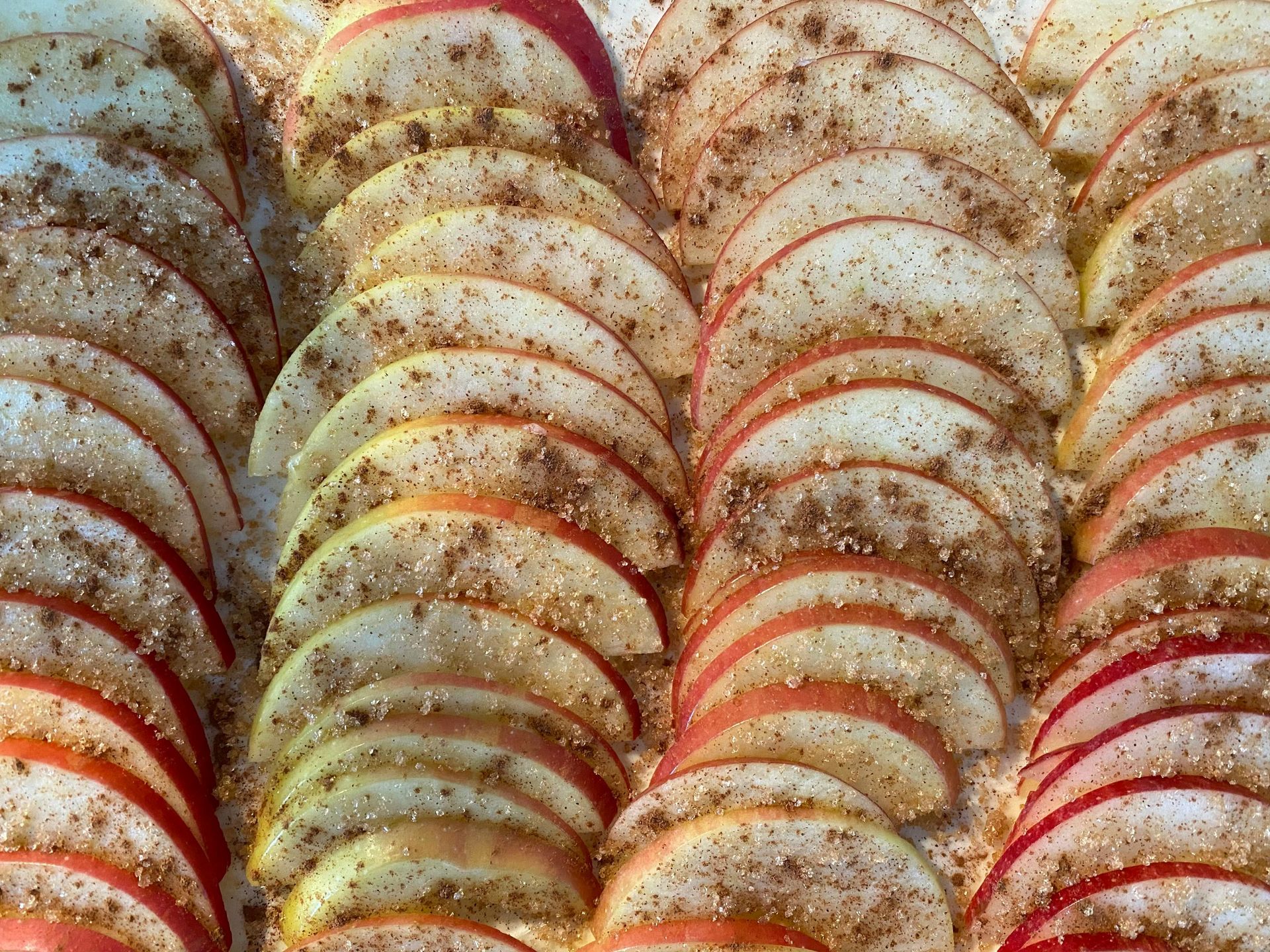 Thinly sliced apples arranged in rows, sprinkled with cinnamon and sugar.