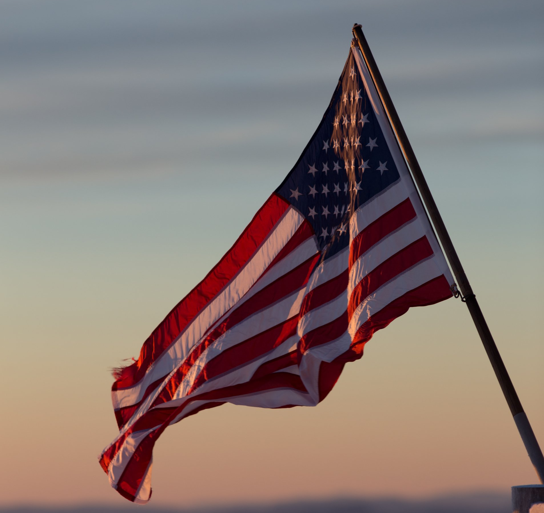 American flag waving in the wind against a twilight sky.