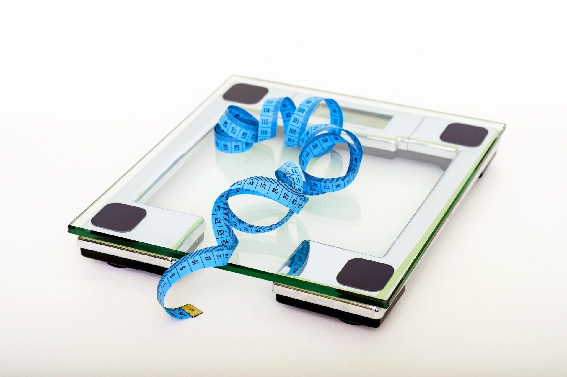 Bathroom scale with blue measuring tape on a white background.
