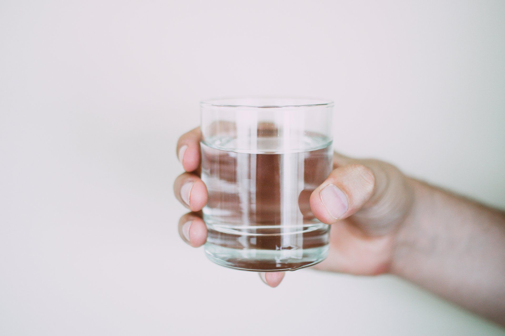 Hand holding a clear glass filled with water.