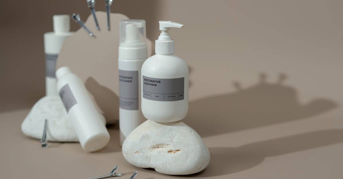White cosmetic product bottles on white stones, neutral background, minimalist aesthetic.