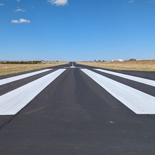 A runway with white stripes on it and a blue sky in the background