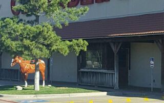 A statue of a horse is standing in front of a building.