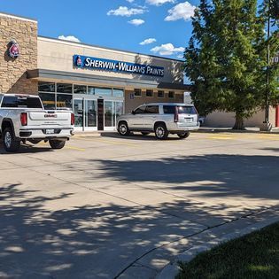 Two trucks are parked in front of a sherwin williams paint store.