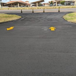 A black asphalt road with yellow arrows painted on it.