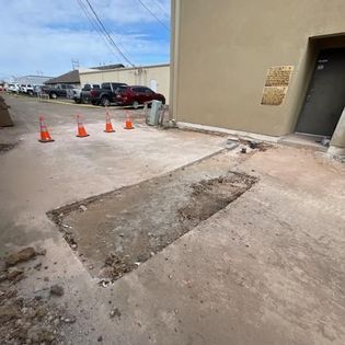 There is a hole in the sidewalk in front of a building.