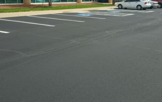 A white car is parked in a handicapped parking spot in a parking lot.