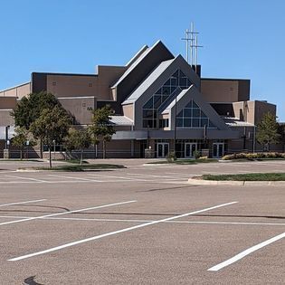 A large building with a lot of windows is sitting in a parking lot.