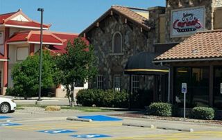 A car is parked in a handicapped parking spot in front of a restaurant.