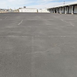 A large empty parking lot with a building in the background.