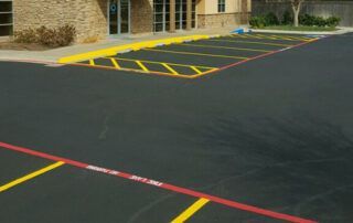 A parking lot with yellow lines and red lines in front of a building.