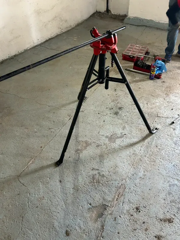A pipe bending machine is sitting on the floor in a room.