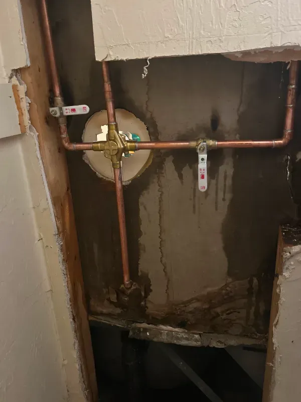 A close up of a copper pipe in a wall.