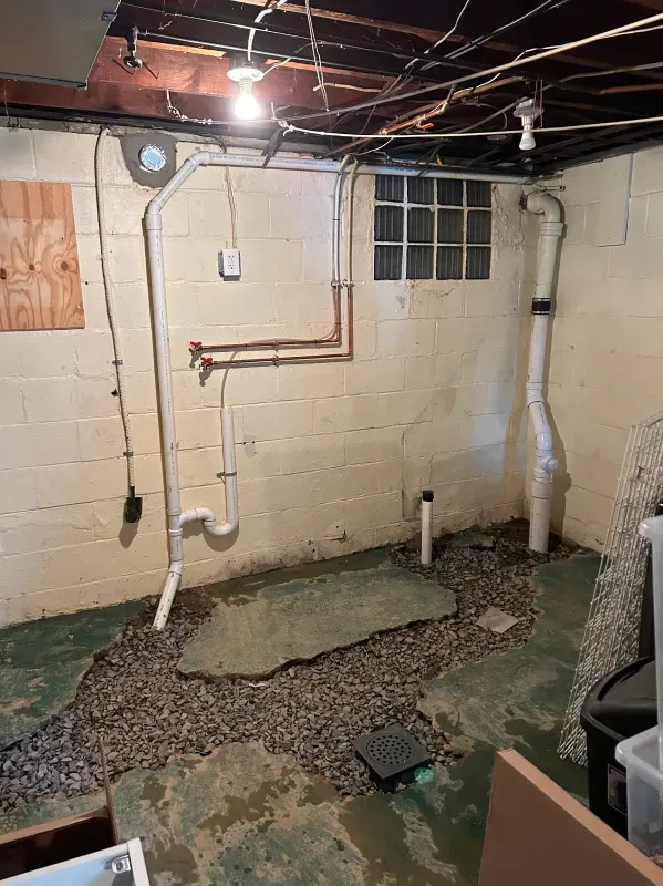 A basement with a lot of pipes and a window.