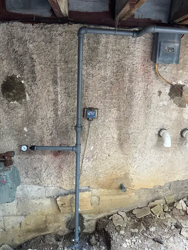 A pipe is connected to a wall in a basement.