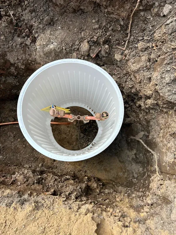 A plastic cup is sitting in the dirt next to a copper wire.