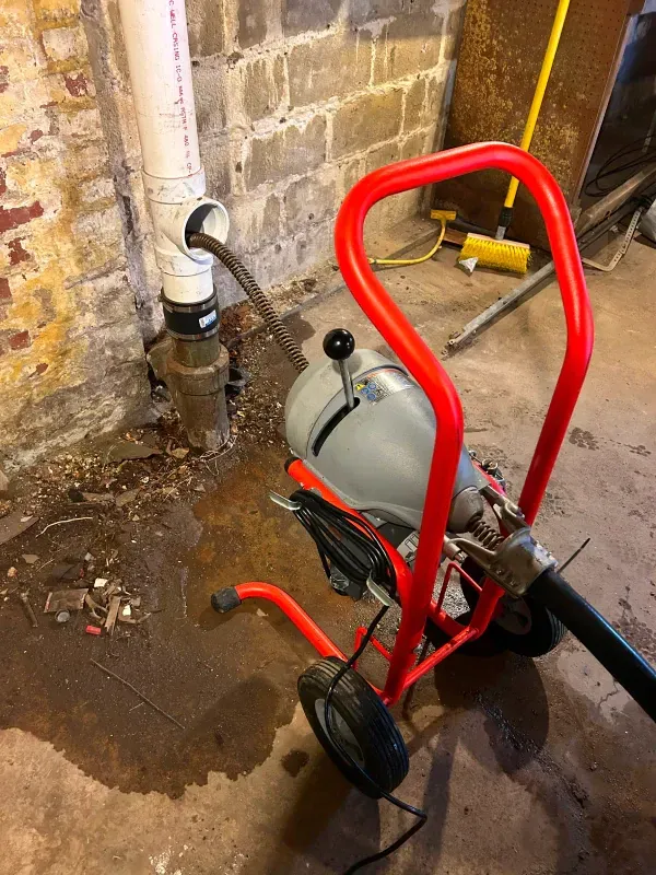 A drain cleaner is being used to clean a pipe in a basement.
