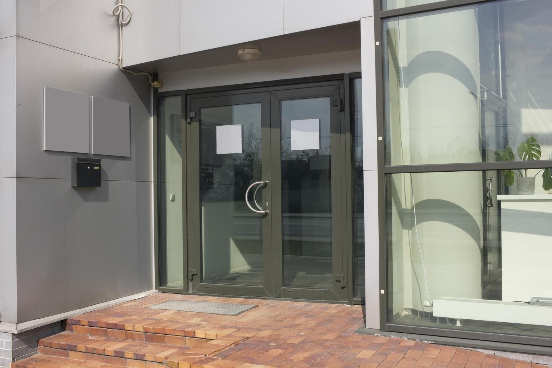 A building with a glass door and stairs leading to it.