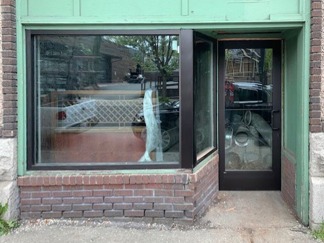 A green building with a black door and a large window