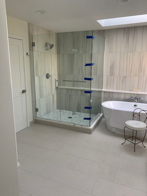 A bathroom with a tub , shower , and skylight.