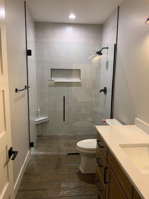A bathroom with a toilet , sink and shower with a glass door.