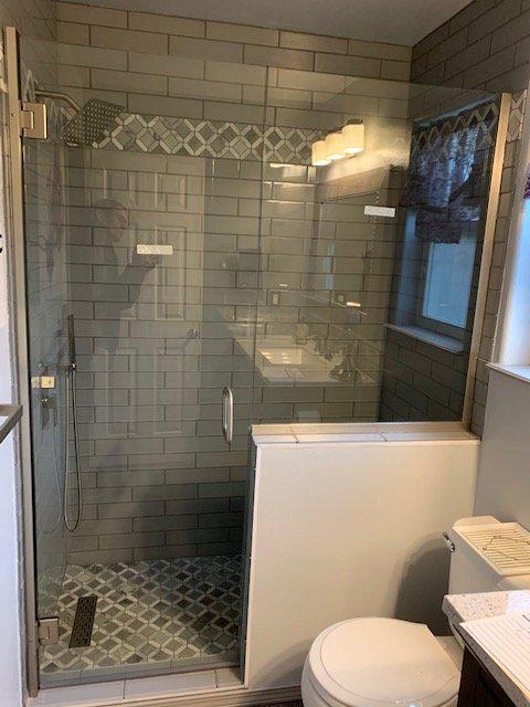 A bathroom with a walk in shower , toilet , sink and mirror.