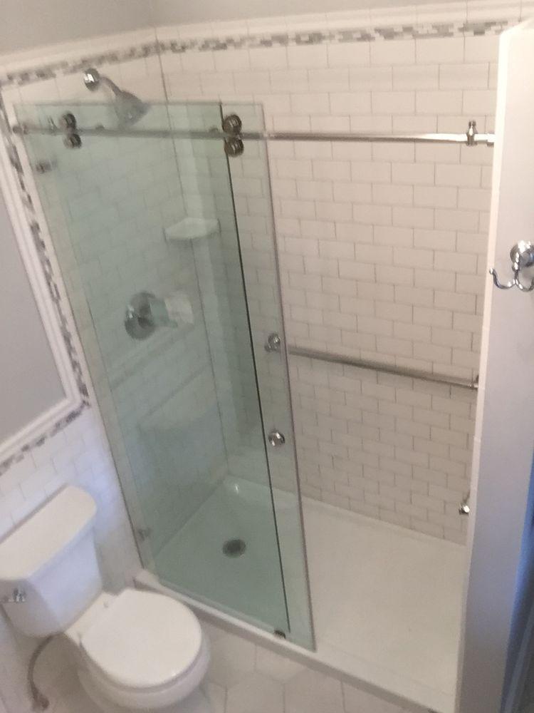 A bathroom with a toilet , shower , and sliding glass door.