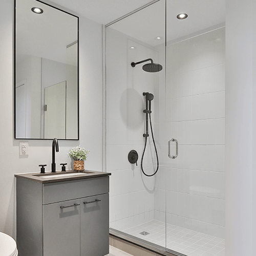 A bathroom with a sink , toilet , shower and mirror.