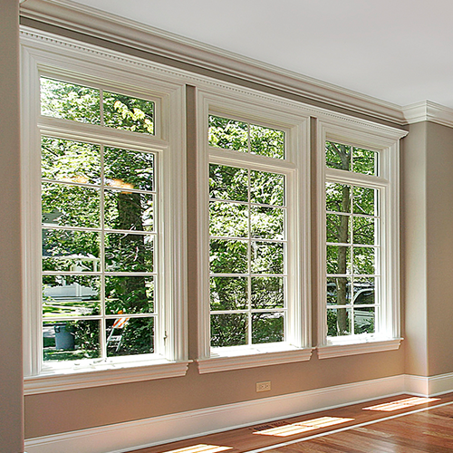 A living room with three windows and a wooden floor.