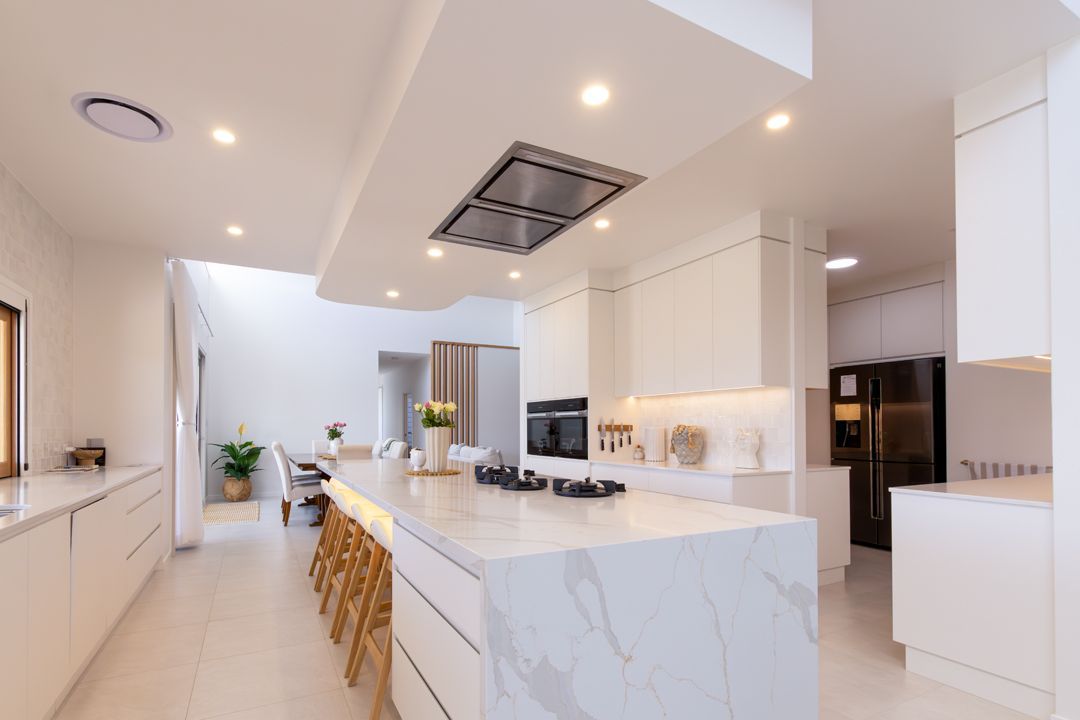 Modern white kitchen with large island and recessed lighting.
