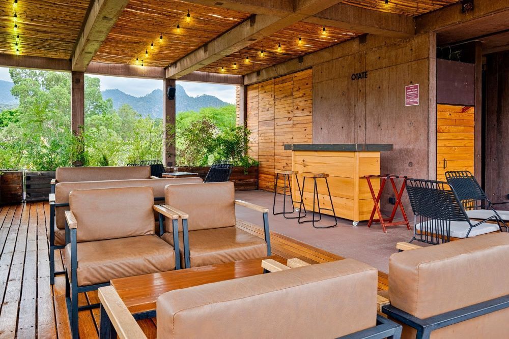 Outdoor seating area with sofas, wooden bar, and mountain views.