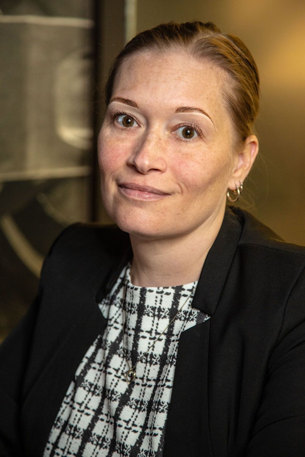 A woman wearing a grey turtleneck is smiling in front of a city skyline