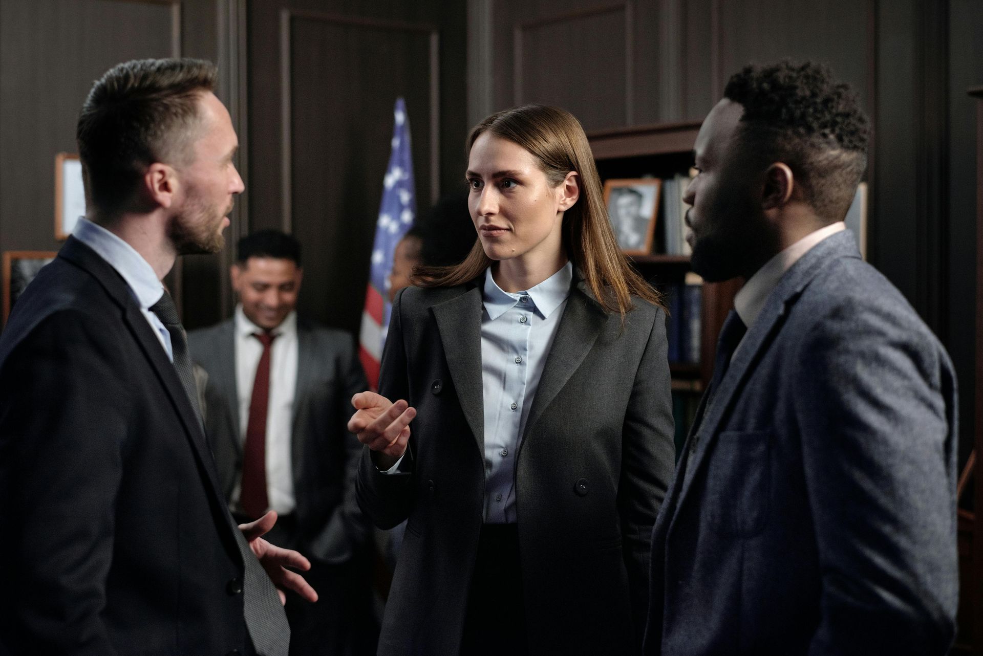 A group of business people are standing in a room talking to each other.